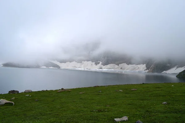 雲と雪に覆われた山脈の湖の雄大な眺め — ストック写真