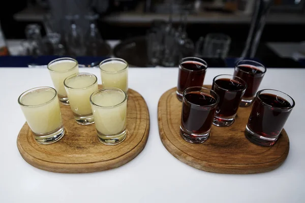 Alcohol shots on a wooden tray stand on the bar counter.