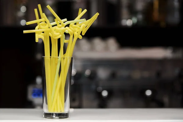 Bright straws for a cocktail in a glass on the bar.