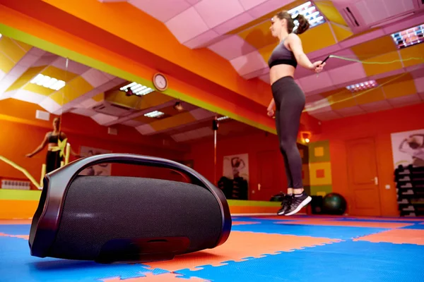Portable acoustics in the aerobics room against the background of a blurred girl on cardio training.