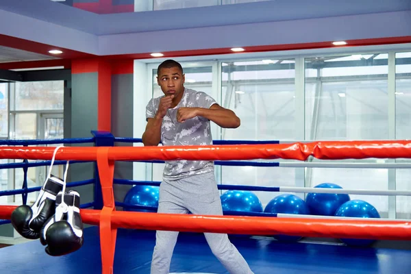 A young man trains in the boxing ring in the gym.