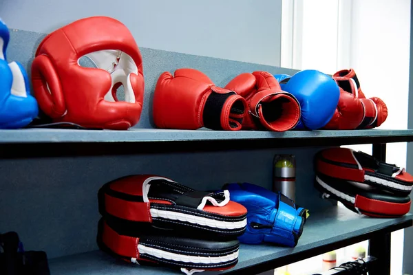 Sports equipment for hand-to-hand combat.A protective helmet, gloves and Boxing paws lie on a shelf.