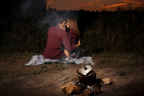 Romantic couple in love late in the evening by the fire on the lake.