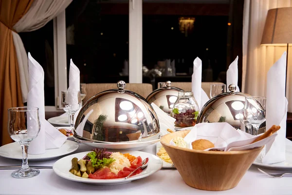 Served dinner table.Hot dish on the dome tray on the server table.