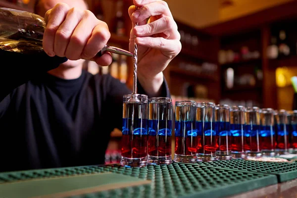 Alcoholic shots on bar counter. Professional bartender pours alcoholic shots.