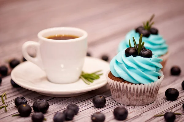 Chocolate cupcakes with blueberries. Cupcakes and a cup of coffee on a table with blueberries. Selective focus.