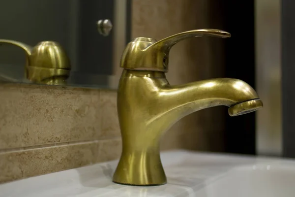 brass faucet on a white porcelain sink in the bathroom