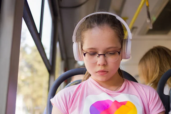 Kız toplu taşıma aracında kulaklıkla müzik dinliyor.