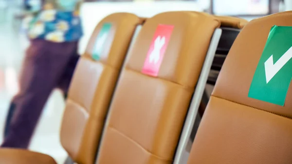 社会的距離 新しいコロナウイルスの拡散を防ぐための社会的距離プロトコルに関するシンボルがマークされた空港の出発エリアの空の椅子の行 タイのCovid — ストック写真