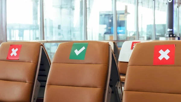 Social distancing, Rows of empty chairs in an airport\'s departure area marked with symbols regarding social distancing protocol to prevent the spreading of novel corona virus, COVID-19 in Thailand