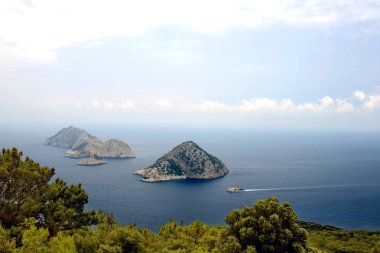 Antalya'da Gelidonya deniz feneri. Küçük adalar bir çam ağacını çerçeveledi. Küçük bir balıkçı teknesi crusing.