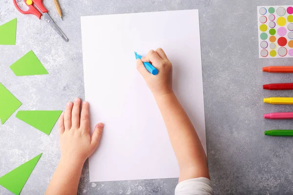 Child draws a pencil drawing empty space colorful grey background top view