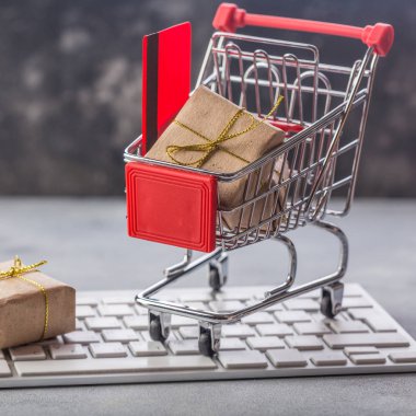 Noel ve yeni yıl hediye kağıt kutusu altın şerit'i bir dizüstü bilgisayar klavye üzerinde küçük bir alışveriş sepeti. Online.e-ticaret veya elektronik ticaret hakkındaki kavramları satın alma veya satma evde bir hareket olduğunu