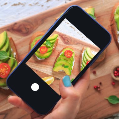 Avokado, krem peynir, tohum ve kiraz Beyaz ahşap zemin üzerine koyu siyah ekmek ekmek taze ile yapılan üzerinde avokado sandviç dilimlenmiş