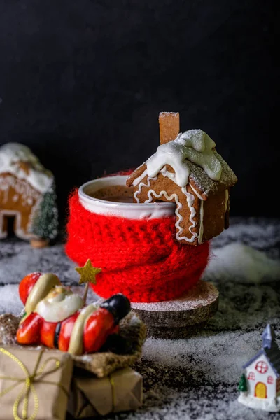Hot cacao or cappuccino decorated with homemade gingerbread house. Christmas or New Year drink and treats concept
