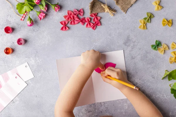 Paper crafts for mother day, 8 march or birthday. Small child doing a bouquet of flowers out of colored paper and colored pasta for mom. Simple gift idea. copy space