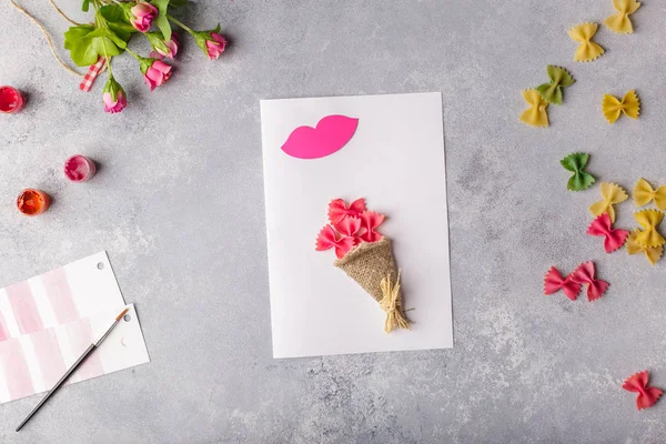 Paper crafts for mother day, 8 march or birthday. Small child doing a bouquet of flowers out of colored paper and colored pasta for mom. Simple gift idea. copy space