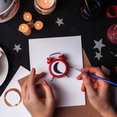 Çizim Araçları'nda sanat stüdyosu. Konsept: uykulu ressam. Kadın eller. Boş sayfa ortasında kırmızı bir saat gece zaman ay gösterilen rahatsız etmeyin. Boya fırçaları yağlı boya darbeleri karışımı ve pape mockup paletinin yanındaki fotoğrafı üstten görünüm