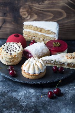 Çeşitli restoran tatlılar siyah kurulu ayarlayın. Farklı tatlı aperatifler kiraz