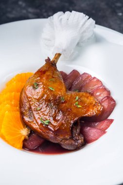 Kızarmış ördek bacak bölümünü portakal ve armut ile restoranda servis tabağı koyu arka plan üzerine ev yapımı köfte servis