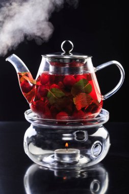 Sıcak bitkisel ve meyve çay zencefil, limon, çilek ve siyah yansıma ile şeffaf çaydanlık nane