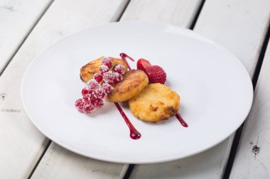 Süzme peynirli gözleme, syrniki, lor börek Beyaz ahşap arka plan beyaz plaka üzerinde taze çilek ile