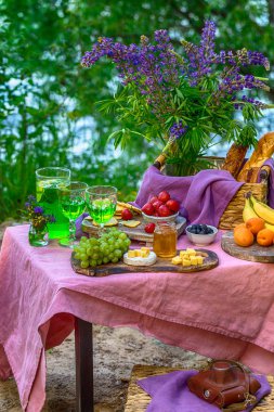 Orman meyve ve sebze çiçekler ile masada su yakın piknik