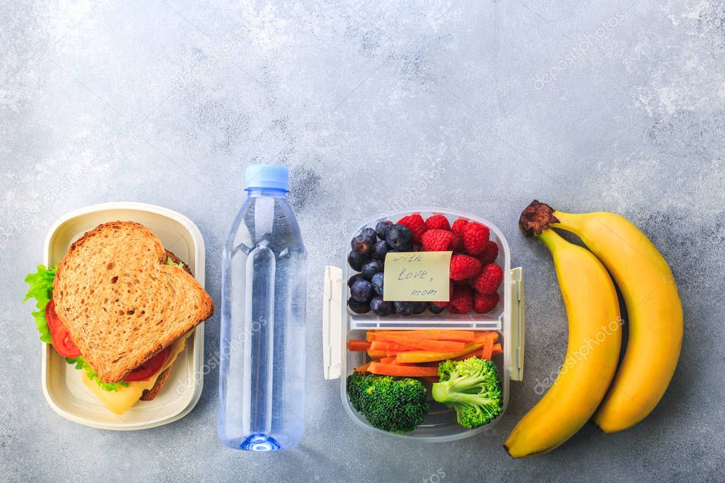 Lunchboxes with sandwiches and different products on grey background