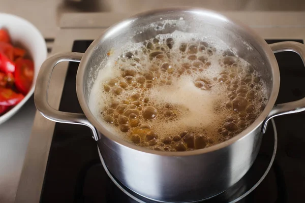Кипящий суп в кастрюле на электрической плите на кухне — стоковое фото