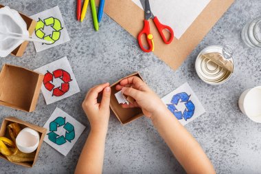 Kız elleri gri arka plan renkli kağıt içinde geri dönüşüm oyunu yapıyoruz