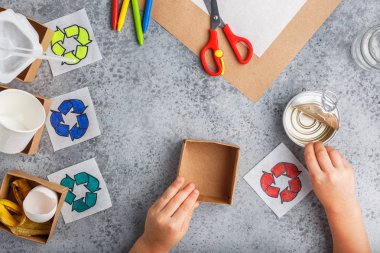 Kız elleri gri arka plan renkli kağıt içinde geri dönüşüm oyunu yapıyoruz