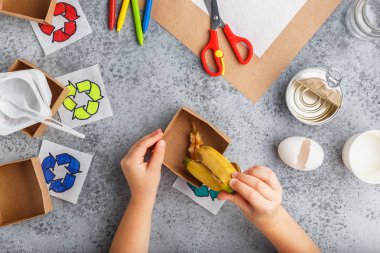 Kız elleri gri arka plan renkli kağıt içinde geri dönüşüm oyunu yapıyoruz
