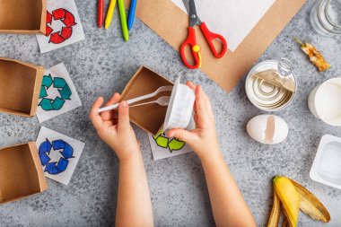Kız elleri gri arka plan renkli kağıt içinde geri dönüşüm oyunu yapıyoruz
