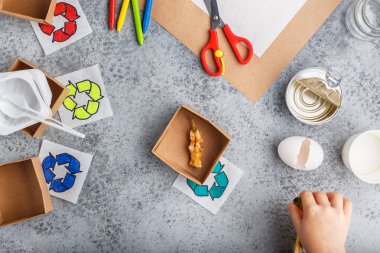 Kız elleri gri arka plan renkli kağıt içinde geri dönüşüm oyunu yapıyoruz