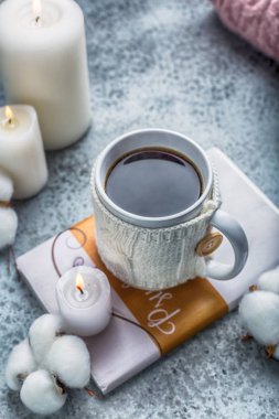 hugge tarzı etrafında kitap mumlar ve pamuk üzerine yerleştirilen beyaz örme kapak sıcak içecek fincan