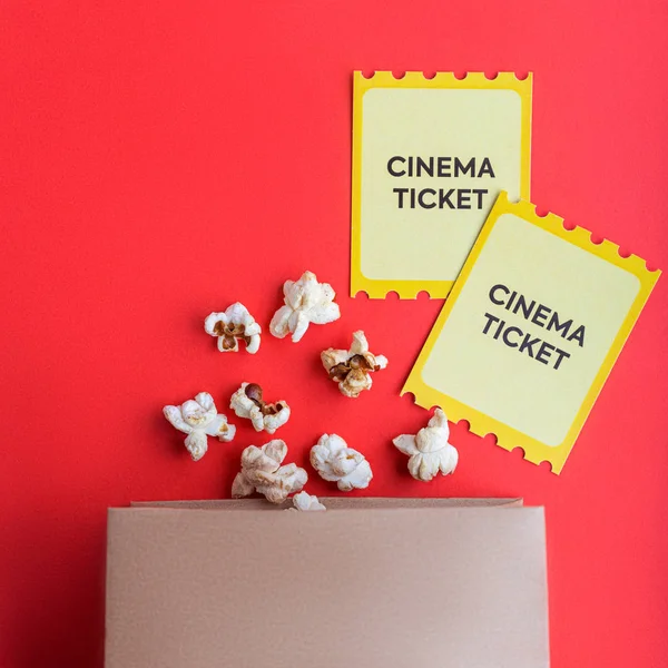 Craft Bag med popcorn och två gula biobiljetter på röd bakgrund flatlay — Stockfoto