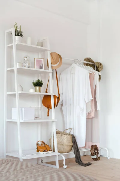 Hanger with clothes in trendy pastel colour on a rack with accessories in a cozy Scandinavian style