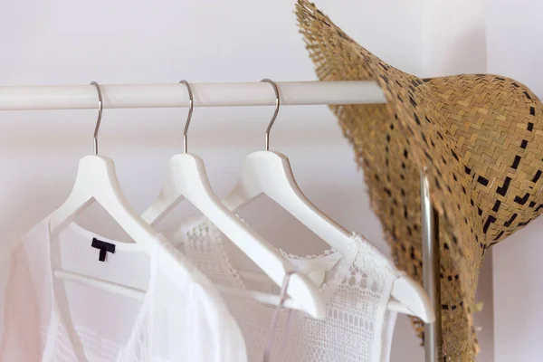 Clothing from eco organic cotton in trend colors and accessories hang on a hanger near a white wall