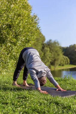 Şehir parkında yoga yapan birinden esinlendim. Spor salonu ve yaşam dengesi konsepti. Aşağı bakan köpek pozu veya Adho mukha shvanasana