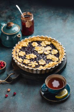 Sonbahar masasında çay partisi, böğürtlenli turta ve bir fincan sıcak çay. Üst görünüm