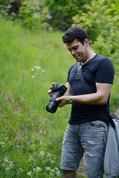 Profesyonel fotoğraf makinesiyle fotoğraf çeken bir adam dağın tepesinde güzel bir manzara. 