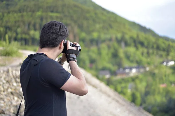 Profesyonel fotoğraf makinesiyle fotoğraf çeken bir adam dağın tepesinde güzel bir manzara. 