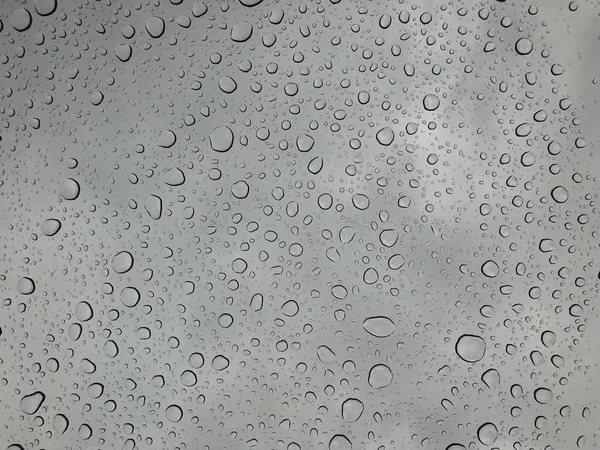 窗玻璃上的雨滴雨落在多云背景下的雨滴背景自然模式 — 图库照片