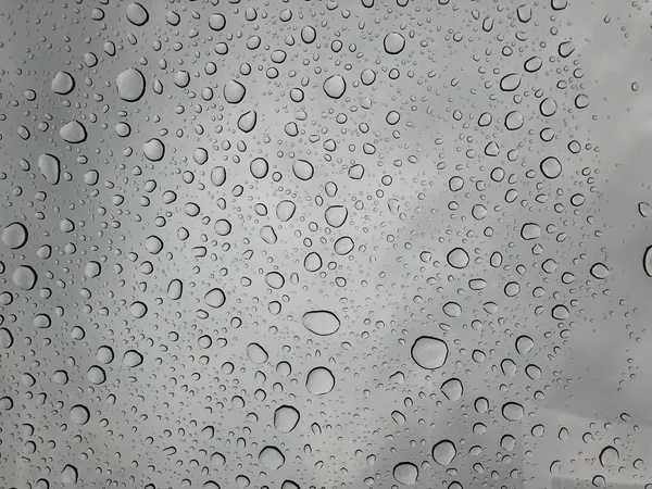 窗玻璃上的雨滴雨落在多云背景下的雨滴背景自然模式 — 图库照片