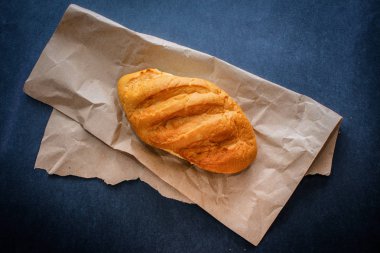 sadece soba gelen masada ekmek. Kraft kağıt üzerinde karanlık bir arka plan üzerinde taze pişmiş ekmek.
