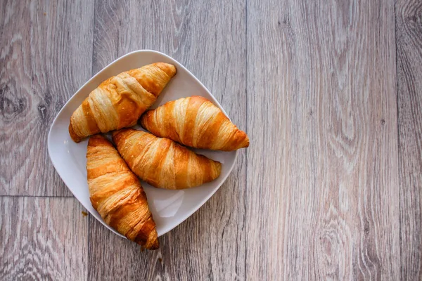 A rich variety of food photography Croissant.Delicious croissants on a square white plate on a wooden tabletop.