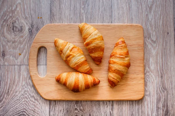 A rich variety of food photography Croissant.Four croissants on a wooden light cutting board on a wooden tabletop.
