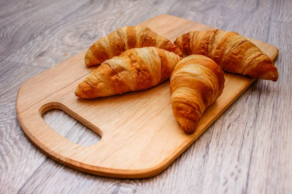 A rich variety of food photography Croissant.Four croissants on a wooden light cutting board on a wooden tabletop.