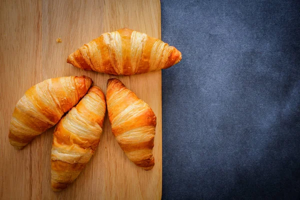 A rich variety of food photography Croissant.Four croissants on a wooden light cutting board on dark craft paper.