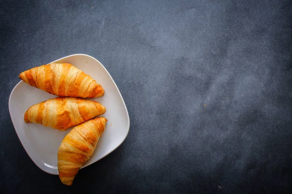 A rich variety of food photography Croissant.Four croissants on brown craft paper on a dark contrasting background.